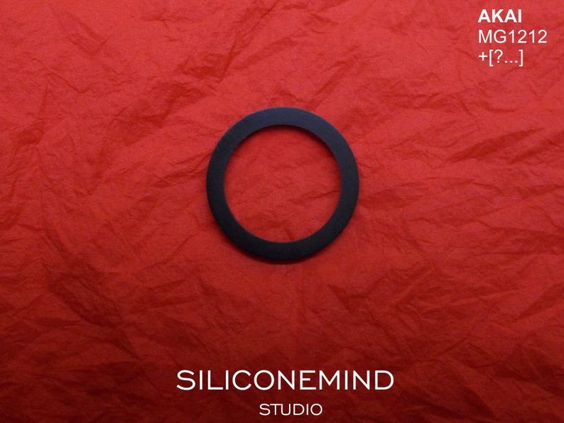 May include: A black ring on a red textured background. The text "AKAI MG1212 +[?...]", "SILICONEMIND STUDIO" is visible on the image.