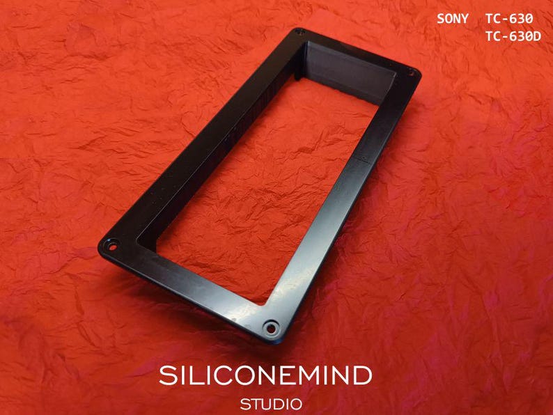 K&ouml;nnte beinhalten: Ein schwarzer rechteckiger Rahmen mit einer hohlen Mitte und vier Schraubl&ouml;chern an den Ecken, konzipiert f&uuml;r die Modelle Sony TC-630 und TC-630D. Der Rahmen hat eine glatte, flache Oberfl&auml;che und ist schr&auml;g positioniert, mit dem Text SONY TC-630 TC-630D in der oberen rechten Ecke und SILICONEMIND STUDIO am unteren Rand.