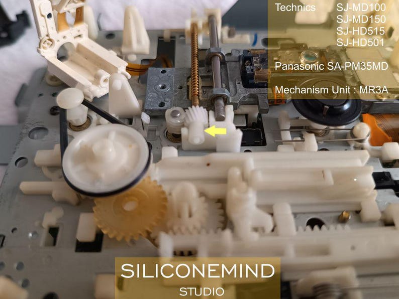 May include: Detailed view of a dismantled electronic mechanism featuring white and beige plastic parts, gears, and metal rods. Text includes "Technics," model numbers, "Panasonic SA-PM35MD," and "Mechanism Unit: MR3A." The logo "SILICONEMIND STUDIO" is also visible.