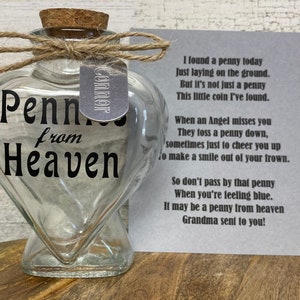 May include: A glass heart-shaped bottle with a cork stopper and a silver tag that says "Connor". The bottle is filled with pennies and has the words "Pennies from Heaven" printed on it. A card with a poem about pennies from heaven is next to the bottle.