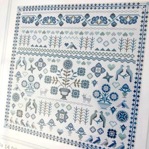 May include: A counted cross stitch kit with a detailed design in shades of blue and white. The design includes floral, bird, and geometric patterns, with the text "A Soft Answer" at the top. The kit includes fabric, thread, and a needle.