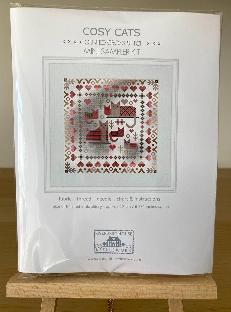 May include: A counted cross stitch kit featuring a design of cats in a cozy setting. The kit includes fabric, thread, needle, chart, and instructions. The finished embroidery will be approximately 6 3/4 inches square.