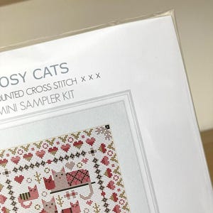 May include: A cross stitch kit featuring a design of cats and hearts. The kit is titled "Crafty Cats" and is a mini sampler kit.