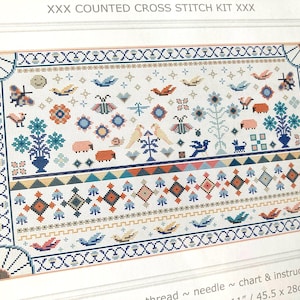 May include: A counted cross stitch kit with a detailed design featuring birds, butterflies, flowers, and geometric patterns in shades of blue, orange, and green. The text "XXX COUNTED CROSS STITCH KIT XXX" is at the top. The finished size is 11 inches by 28 cm.