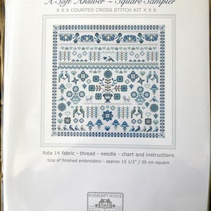 May include: A counted cross stitch kit titled "A Soft Answer - Square Sampler." The design features a detailed, symmetrical pattern in shades of blue and white, including birds, flowers, and geometric shapes. The finished embroidery size is approximately 15 1/2 inches square.