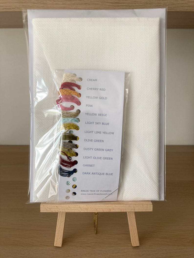 Pu&ograve; includere: Un kit di ricamo a punto croce su tela Aida bianca con una tabella dei colori e gomitoli di filo in crema, rosso ciliegia, oro giallo, rosa, beige giallo, azzurro chiaro, giallo limone chiaro, verde oliva, grigio verde spolverato, verde oliva chiaro, granato e blu antico scuro. Il kit &egrave; etichettato "RR626 Albero di fiori".
