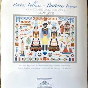 May include: A counted cross stitch sampler kit featuring a colorful design of Breton folkies, a lighthouse, and nautical elements. The kit includes 14 count Aida fabric, threads, a needle, a chart, and instructions. The finished embroidery will be approximately 12 x 9 inches.