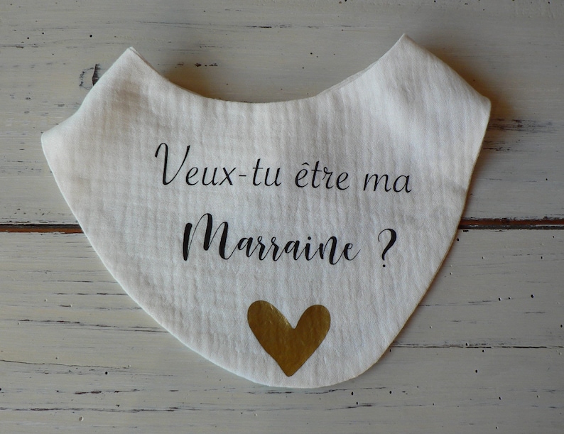May include: White fabric bib with black text that reads "Veux-tu &ecirc;tre ma marraine?" and a gold heart.
