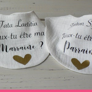May include: Two white bibs with gold hearts and black text. The text on the left bib reads "Tata Laetitia Veux-tu &ecirc;tre ma Marraine?" and the text on the right bib reads "Anton Sylvain Jeux-tu &ecirc;tre mon Parrain?"