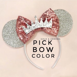 May include: A headband with silver sequined mouse ears and a rose gold sequined bow. A silver glitter crown is centered on the bow. The text "PICK BOW COLOR" is displayed in black.