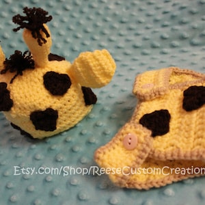 May include: A crocheted giraffe hat and diaper set for a baby. The hat and diaper are yellow with black spots. The diaper has a tail.