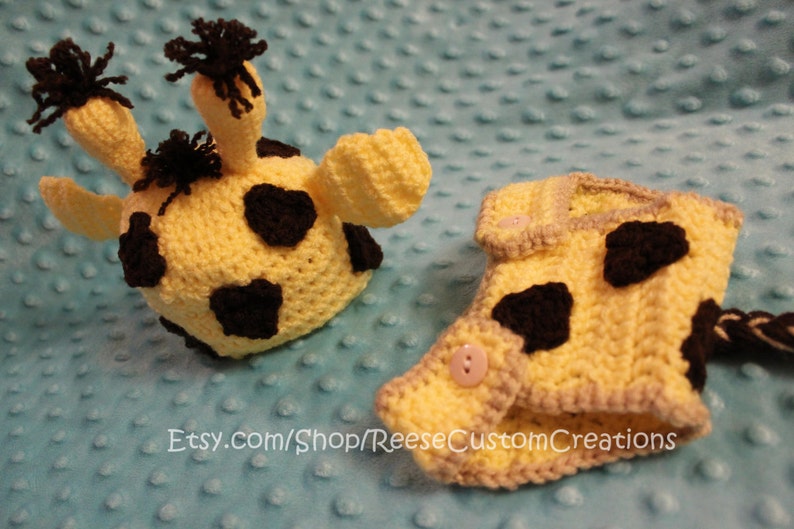 May include: A crocheted giraffe hat and diaper set for a baby. The hat and diaper are yellow with black spots. The diaper has a tail.