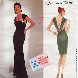 Könnte beinhalten: Eine Schnittmusterhülle für ein Oscar de la Renta Kleid mit einem bodenlangen schwarzen Kleid und einem knielangen grünen Kleid mit tiefem Rückenausschnitt. Die Packung enthält ein Vogue American Designer Original Etikett mit blauen Sternen.
