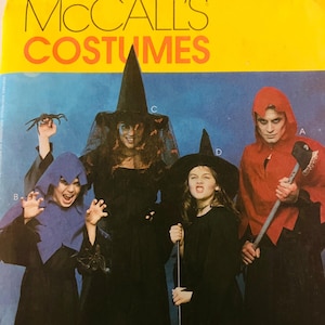 May include: A McCall's Costumes sewing pattern envelope featuring four individuals in Halloween attire. One wears a blue hooded cape, another a black witch costume with a veil, a third a black witch hat, and the fourth a red hooded cape.