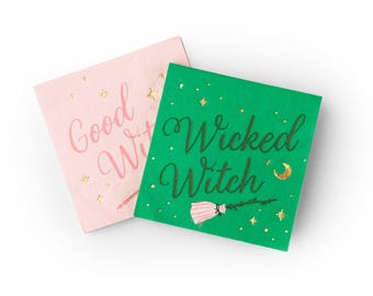 May include: Two square paper napkins, one pink and one green, with gold accents. The pink napkin reads "Good Witch" in cursive, while the green napkin says "Wicked Witch" with a broom illustration. Festive and themed for Halloween.