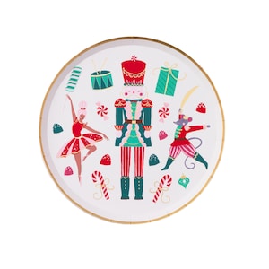 May include: A round white paper plate with a gold rim, featuring a festive Nutcracker theme. The design includes a Nutcracker soldier, a ballerina, a mouse, candy canes, and Christmas presents. The plate is decorated with red, green, and teal accents.