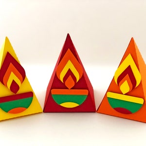 May include: Three colorful, pyramid-shaped paper decorations. Each has a flame design in shades of red, orange, and yellow, above a green and yellow bowl shape. The pyramids are yellow, red, and orange.