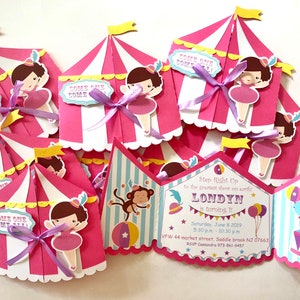 Puede incluir: Invitaciones de fiesta de circo de color rosa y blanco con una cinta morada. La invitaci&oacute;n dice "Step Right Up to the greatest show on earth! Londyn is turning 1!" con la fecha y la hora de la fiesta.