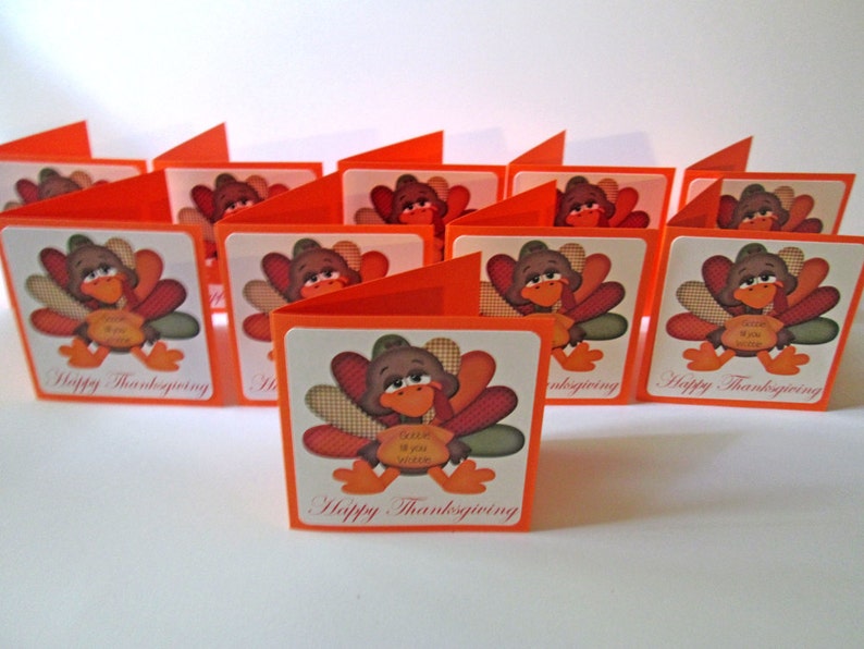 May include: A collection of Thanksgiving greeting cards. Each card features a cartoon turkey illustration with a brown head, colorful feathers, and orange feet. The cards are orange and white, with the text "Happy Thanksgiving".