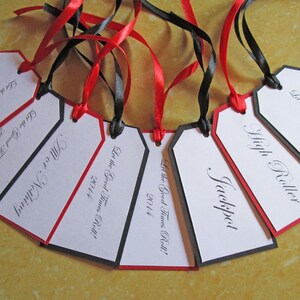 May include: A set of six white gift tags with black and red trim. Each tag has a different name written in black cursive script. The text "Let the Good Times Roll!" and the year "2014" are printed on each tag.