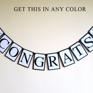 May include: A black and white banner with the word "CONGRATS" in large, bold letters. The banner is strung together with black string and has small black graduation caps with stars on each end.