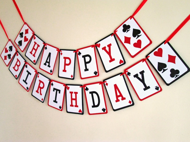 K&ouml;nnte beinhalten: Ein festliches Geburtstagsbanner aus Spielkarten-f&ouml;rmigen Ausschnitten. Jede Karte zeigt einen Buchstaben, der "HAPPY BIRTHDAY" in Rot und Schwarz auf wei&szlig;em Hintergrund schreibt. Die Karten sind mit einem roten Band verbunden.