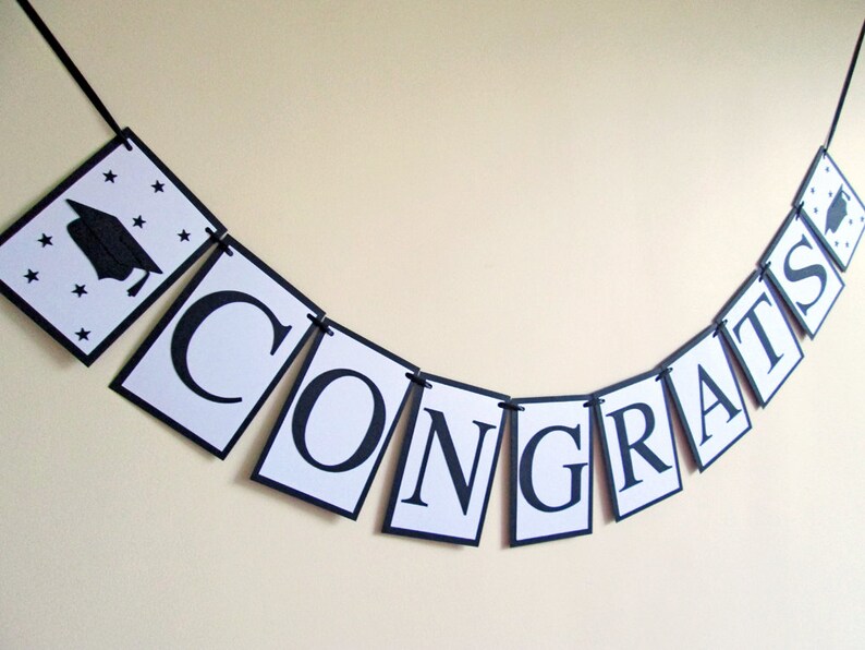 May include: Black and white graduation banner with the word "CONGRATS" and a graduation cap with stars on the first flag.