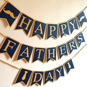 May include: A navy blue banner set with gold lettering and accents. The banner reads "HAPPY FATHER'S DAY" and includes mustache and tie graphics. The banner is strung with gold ribbon, perfect for a Father's Day celebration.