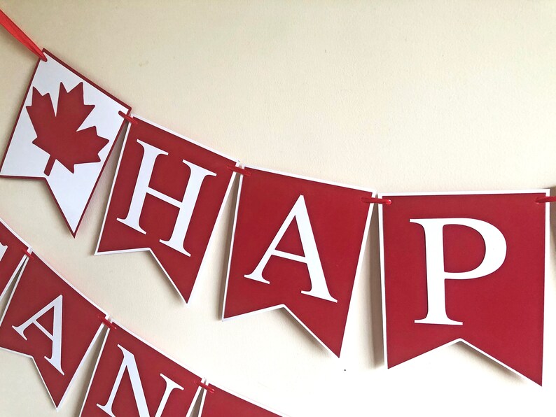 May include: Red and white banner with the words "HAPPY" in white letters on a red background. The banner is decorated with a red maple leaf on a white background.