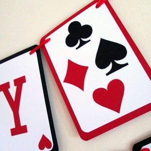 K&ouml;nnte beinhalten: Ein Banner aus Spielkartenformen in Rot, Schwarz und Wei&szlig;. Das Banner zeigt die Farben Herz, Karo, Kreuz und Pik. Der Buchstabe "Y" ist auf einer der Karten zu sehen.