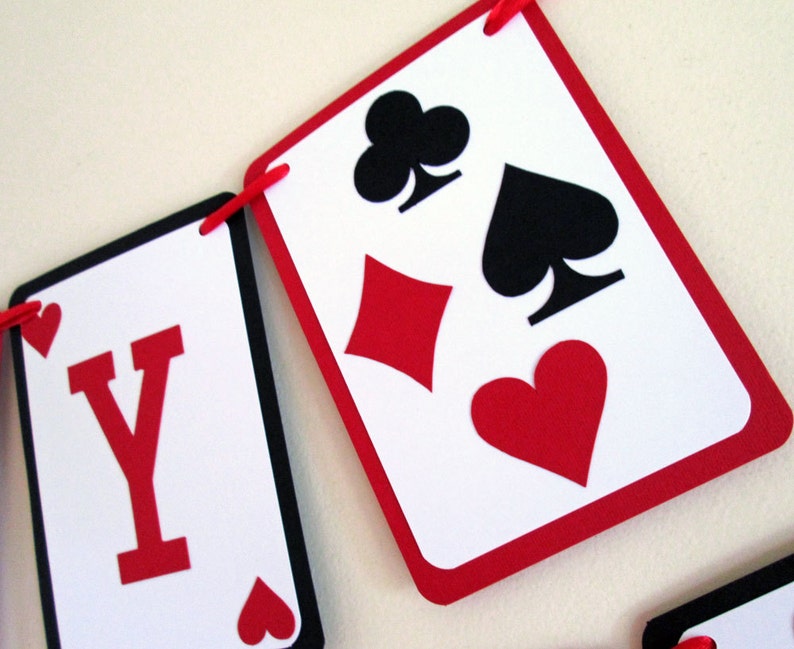 K&ouml;nnte beinhalten: Ein Banner aus Spielkartenformen in Rot, Schwarz und Wei&szlig;. Das Banner zeigt die Farben Herz, Karo, Kreuz und Pik. Der Buchstabe "Y" ist auf einer der Karten zu sehen.
