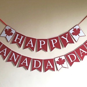 May include: Red and white banner with the text "Happy Canada Day" in white letters. The banner has maple leaf cutouts on each end.