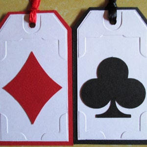 May include: Two white gift tags with red and black borders. The tag on the left has a red diamond shape and the tag on the right has a black clover shape.