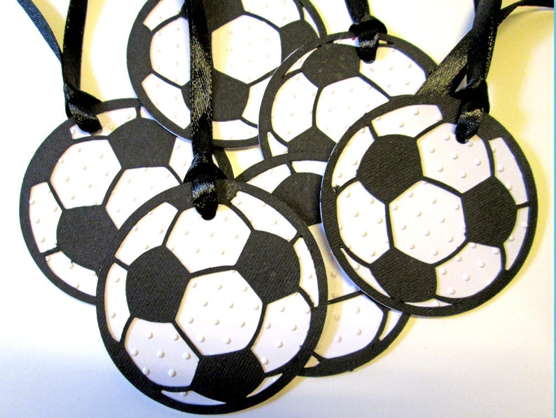 以下が含まれることがあります： 黒と白のサッカーボール型のギフトタグ6個セット。黒いリボン付き。タグは厚紙製で、表面にテクスチャがあります。