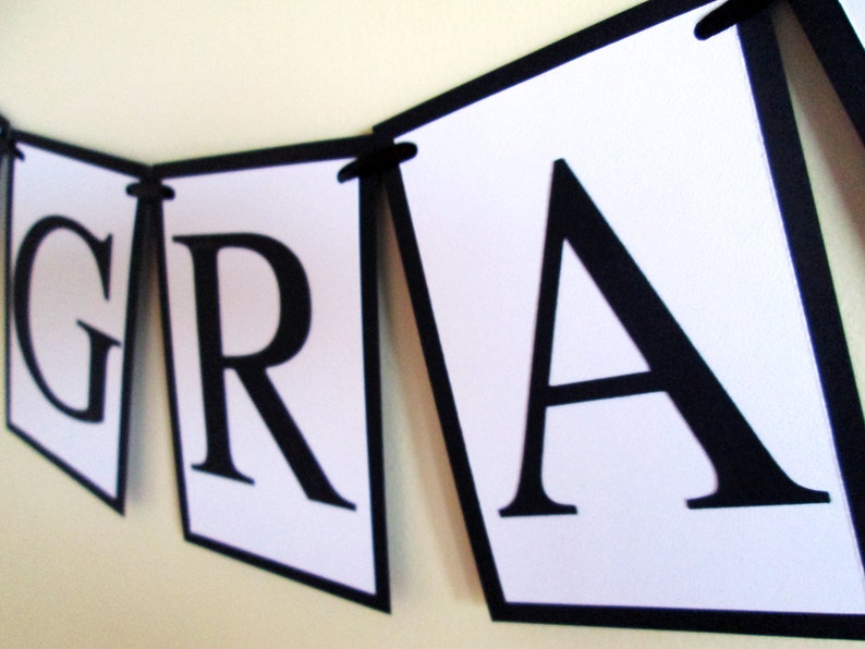 May include: Black and white banner with the word "GRAD" in large, bold letters. Each letter is on a separate white triangle with a black border.