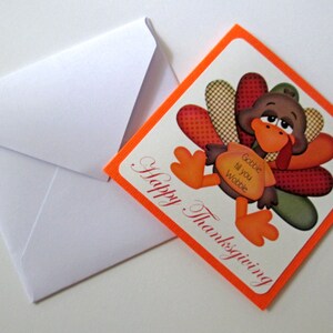May include: Thanksgiving greeting card with a cartoon turkey illustration. The turkey has brown feathers, an orange beak and feet, and a red wattle. The card reads "Happy Thanksgiving" and "Gobble til you Wobble". A white envelope is next to the card.