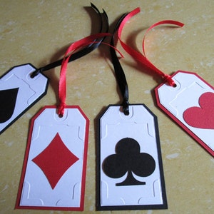 May include: Four white gift tags with black and red borders. Each tag features a different playing card suit: spades, diamonds, clubs, and hearts. The tags are tied with black and red ribbon.