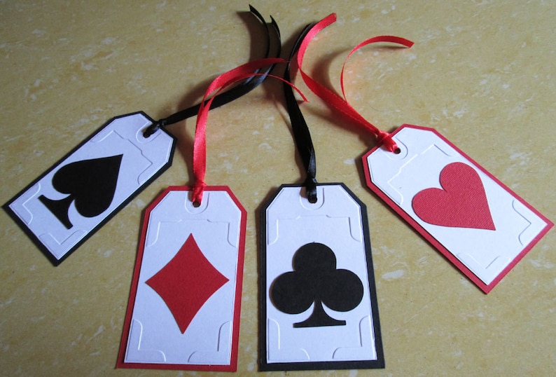 May include: Four white gift tags with black and red borders. Each tag features a different playing card suit: spades, diamonds, clubs, and hearts. The tags are tied with black and red ribbon.