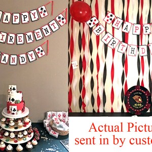 K&ouml;nnte beinhalten: Eine festliche Party-Szene mit Dekorationen im Casino-Stil. Banner mit den Aufschriften "HAPPY RETIREMENT SANDY" und "HAPPY BIRTHDAY" in Spielkarten-Designs. Eine mehrst&ouml;ckige Torte und Cupcakes werden pr&auml;sentiert, zusammen mit Luftballons und einem Casino-Chip.