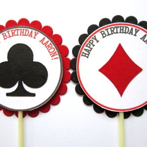 Peut inclure: Deux d&eacute;corations rondes pour cupcakes avec des bords festonn&eacute;s rouges et noirs. Les d&eacute;corations pr&eacute;sentent un cercle blanc avec du texte noir qui dit "Happy Birthday Aaron!" et un tr&egrave;fle noir ou un carreau rouge au centre.