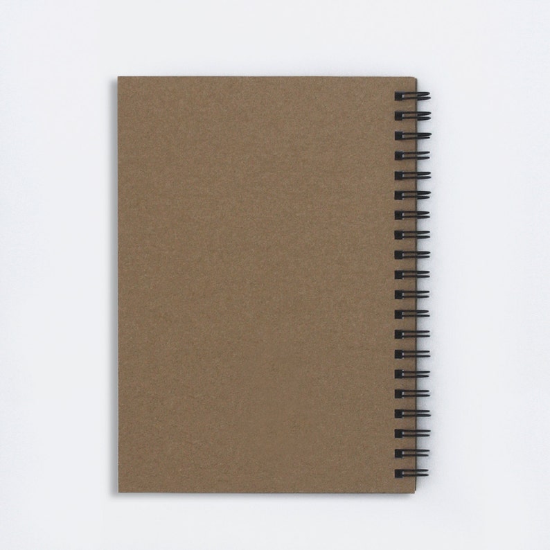 Puede incluir: Un cuaderno de espiral marr&oacute;n con una portada en blanco.