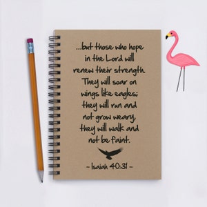 May include: A brown notebook with a spiral binding and a quote from Isaiah 40:31. The quote reads, "...but those who hope in the Lord will renew their strength. They will soar on wings like eagles; they will run and not grow weary, they will walk and not be faint." A pink flamingo is on the right side of the notebook.
