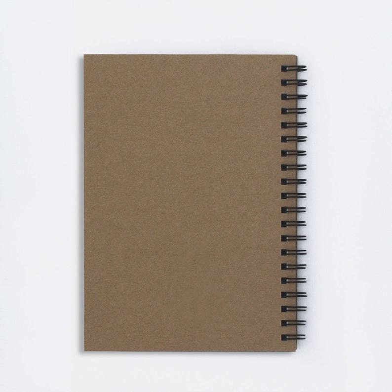 May include: A brown spiral-bound notebook with a textured cover. The notebook's pages are held together by a black metal spiral binding along the left edge. The cover is a solid, neutral brown color.