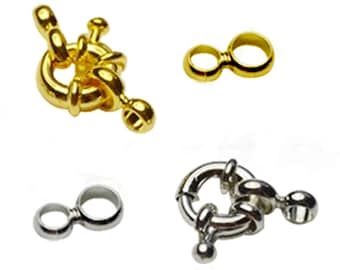May include: Four jewellery clasps in gold and silver tones are displayed against a white background. The clasps include a lobster claw clasp, a figure-eight clasp, and two other styles. These clasps are used for necklaces and bracelets.