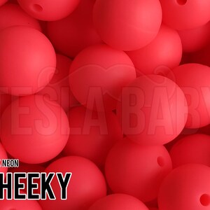 May include: A close-up of a pile of bright red silicone beads. The beads are smooth and round, and they are arranged in a random pattern. The text "DARK NEON CHEEKY" is visible in the lower left corner of the image.