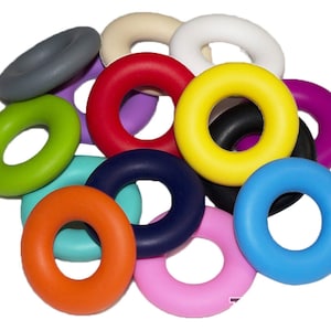 May include: A set of 13 colorful silicone rings, each with a different color, including red, yellow, green, blue, purple, orange, pink, white, black, and gray. The rings are all the same size and shape, and they are arranged in a pile.