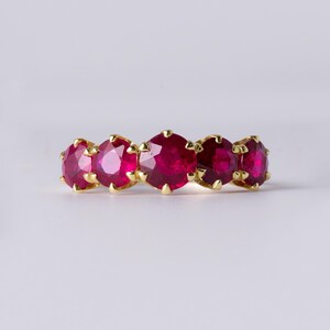 Puede incluir: Un anillo de banda de oro con cinco piedras de rubí rojo engastadas en garras.