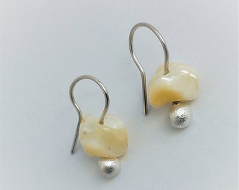 May include: A pair of silver earrings with a white shell and a silver bead. The earrings are simple and elegant.
