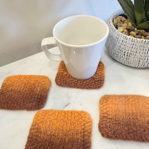 Orange variegated set of 4 square wool coasters, with mug sitting on top of one of the coasters.