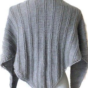 K&ouml;nnte beinhalten: Ein grauer, gestrickter, dreieckiger Schal mit Rippenstruktur. Der Schal ist &uuml;ber eine wei&szlig;e Schaufensterpuppe gelegt.